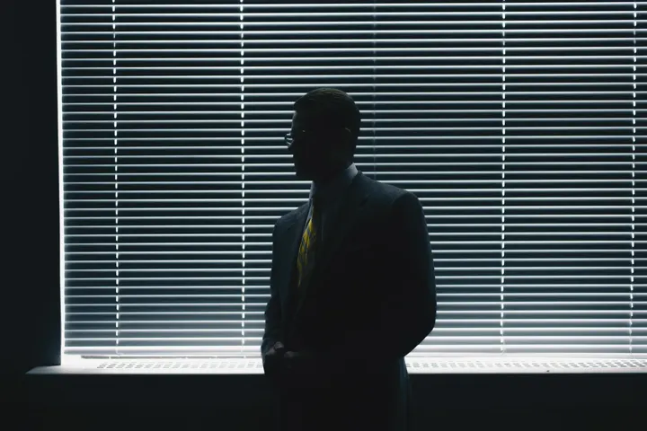 Silhueta de um homem diante de uma persiana