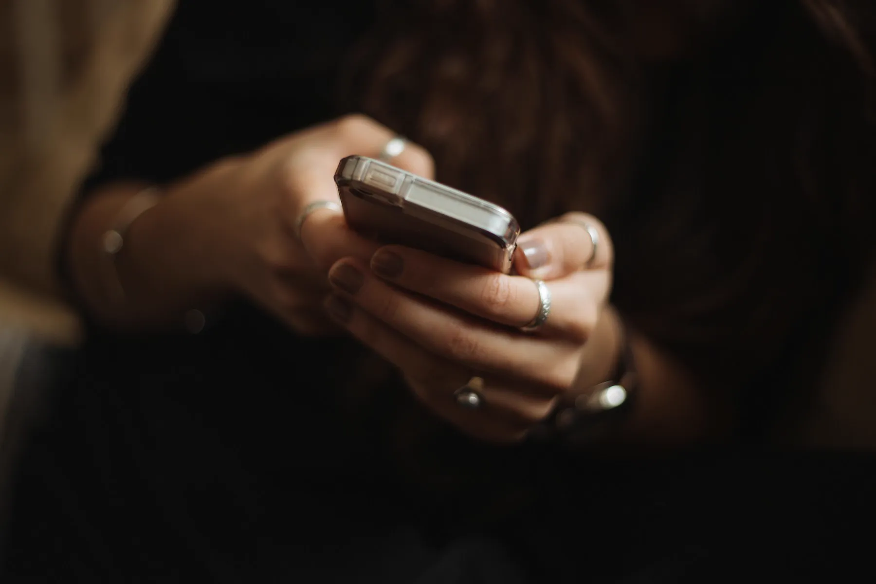 Mãos segurando um celular em ambiente escuro
