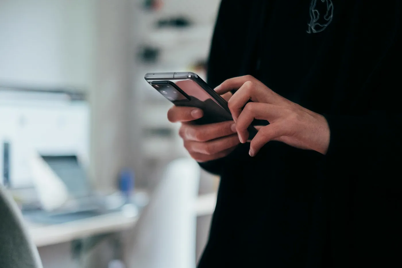 Pessoa usando o celular diante de um caixa eletrônico